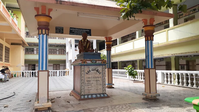which reads "శ్రీశ్రీ యోగి" (Sri Sri Yogi), indicating the figure is a Yogi. The setting, with multiple-story buildings surrounding the courtyard,